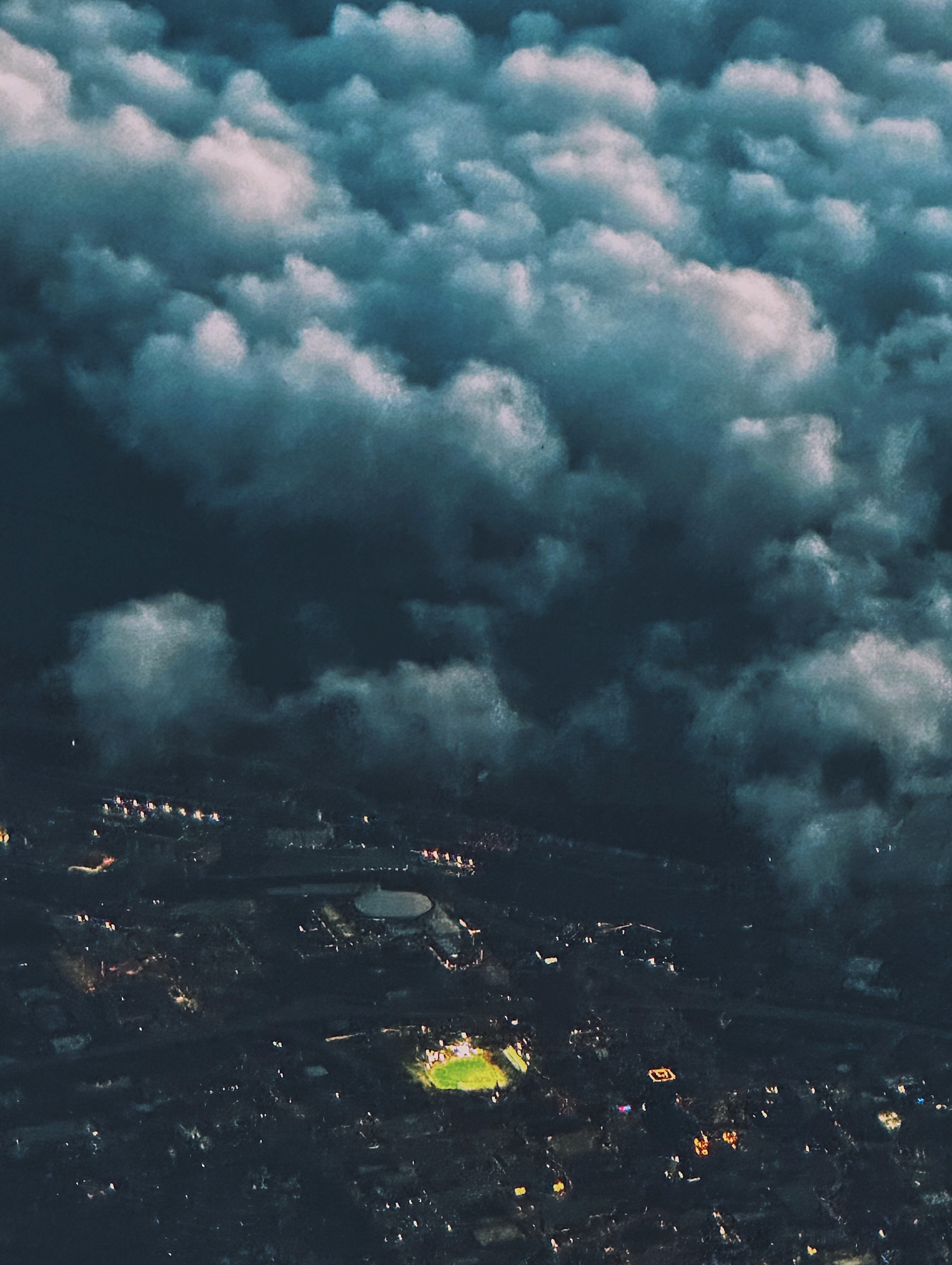 Aerial view of a lit baseball diamond under clouds